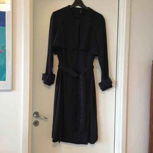  - Mörkblå trenchcoat från H&M trend. Använd två gånger så i mycket fint skick.  ”Siden”detaljer på fickor samt midjeband. 