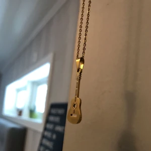  - Ett guldigt halsband med en gitarr på. Jättefint!  Använt ca 2 ggr men säljes pga att jag inte använder det! Frakten ligger på 10kr. Bra kvalite, köpt i Spanien. 
