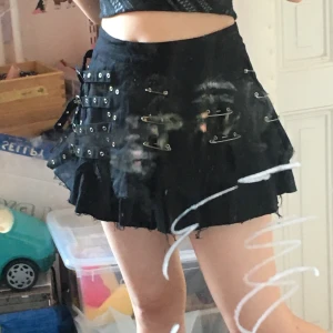 Gothkjol med säkerhetsnålar  - Skitcool gothkjol med säkerhetsnålar och spännen på! Skulle passa både en punk eller emo brud jättebra, egentligen nästan alla alternativa subkulturer. Den sitter superbra och har ett jättesjysst naturligt”poff” till den. Kjolen är knappt använd och i jättebra skick. Hittade den på en loppis, men den hade fortfarande lappen på sig då så tror inte den använts många gånger.  Om du vill ha detaljer om tvättlappen mm är det bara att höra av sig. Frakten tillkommer, skickas spårbart. Jag kan även mötas upp på söder i stockholm. Hör gärna av er! Frakt:63kr