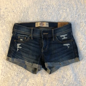 Hollister lowrised Jeansshorts - W:23, lowrised, håliga, köpta i Sverige för någon månad sedan, aldrig använda då jag föredrar highwasted, köptes för 500kr
