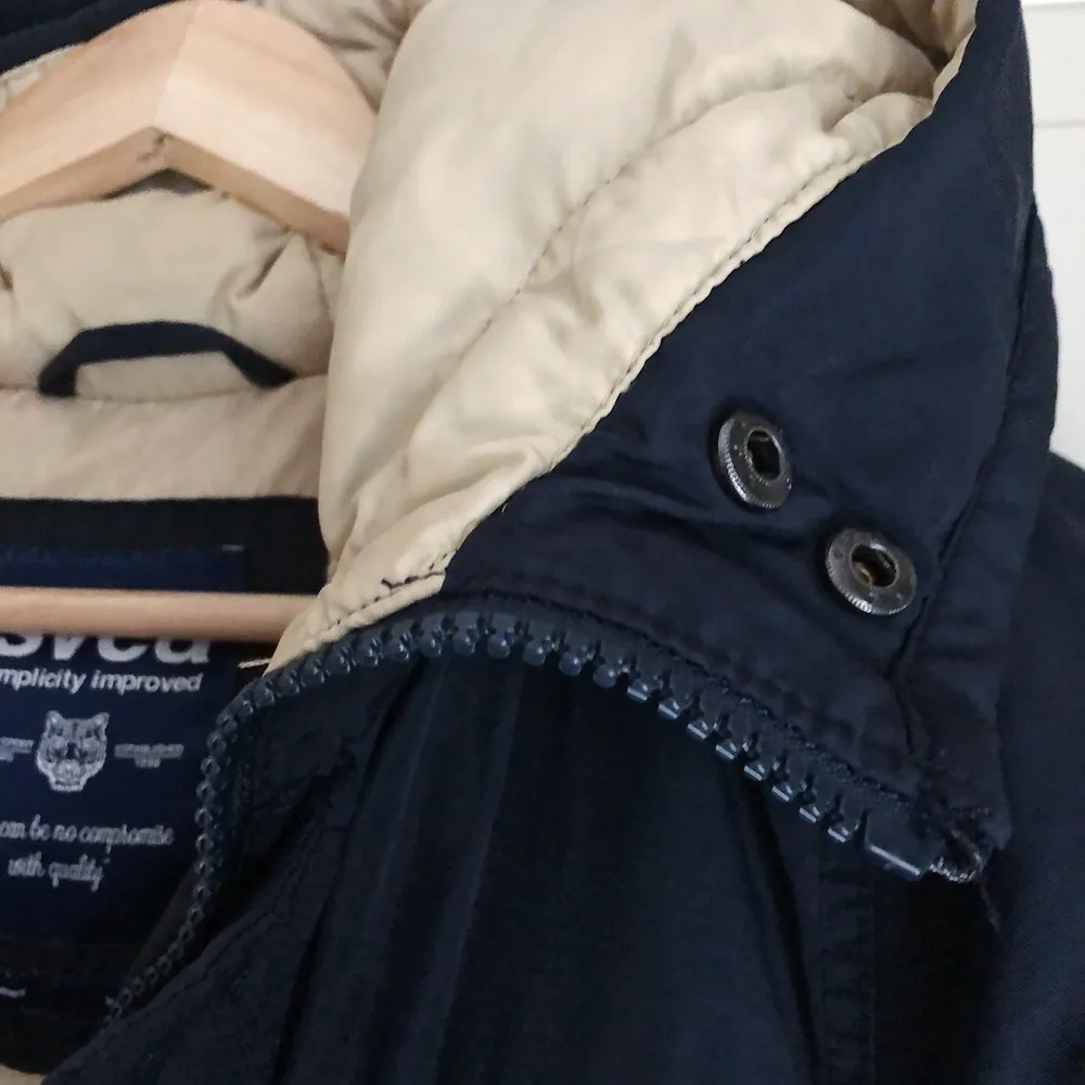 Marinblå vinterjacka med beiget innerfoder i en lite längre modell från SVEA (bomull, nylon, dun, fjäder). Storlek XS, men passar även S. Sparsamt använd.. Jackor.