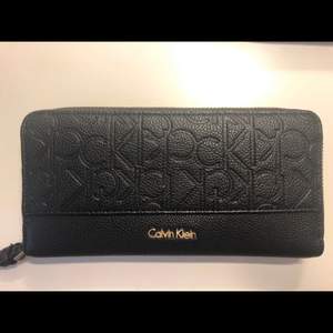 Super fin svart guldig clutch plånbok från Calvin Klein. I fint skick med någon liten repa på guld dragkedjan. Köpt för 900kr i butik