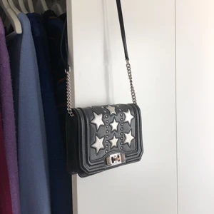Rebecka Minkoff väska med stjärndetaljer - Väska från Rebecka Minkoff i svart läder med silvriga stjärnor. I perfekt skick och använd få gånger. Finns dustbag till och går att justera kedjan. 