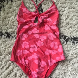 Baddräkt  - Rosa blommig baddräkt med knytning mellan brösten från Gina tricot, använd 1 gång då jag testade den. Köpt för cirka 170kr säljer för 60kr. Köparen står för frakt, priset går att diskuteras💕