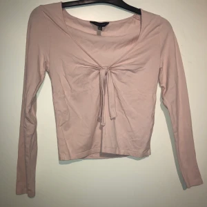 Ljusrosa långärmad  - Söt, lite croppad, långärmad topp med knytning i fram. Stl 40 men skulle snarare säga 38/M. 