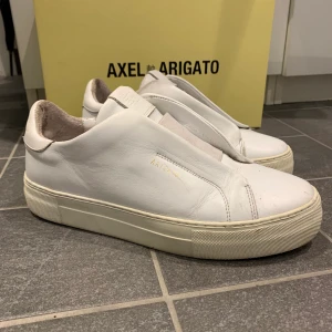 Axel arigato - Vita Axel arigato skor. Modell clean 360 laceless. Box och dustbag finns. Köpta på Nk för 1900kr. Lite slitningar därav de billiga priset!
