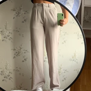 Nakd kostymbyxor strl 34  - Ett par gråa kostymbyxor med vita ränder. Strl 34. Fraktkostnaden står köparen för!😊