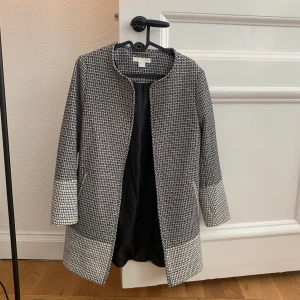 Gråmönstrad kappa  - Kappa från H&M Stl: 36 Enbart använd vid ett fåtal tillfällen så kappan är i mycket bra skick. Finns att hämta vid Östermalmstorg eller skickas mot avgift. 