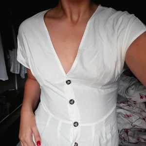  - Lång klänning med knappar och en slit framtill, superhärligt material med en stan gräddvit färg. Helt ny och oanvänd med lappen kvar