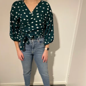 En prickig wrap around blus  - En snygg blus som man knyter runt sig. Den har en variant av ballong armar och sitter fint på. Den är knappt använd och är i storlek S. ☺️