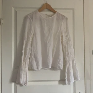 Vit blus med guldiga detaljer från H&M  - Vit långärmad blus med guldiga detaljer och större ärmar från H&M. En knapp i bak på ryggen. I storlek 34 men passar även 36. Från H&Ms L.O.G.G kollektion. Säljer för 60kr. 