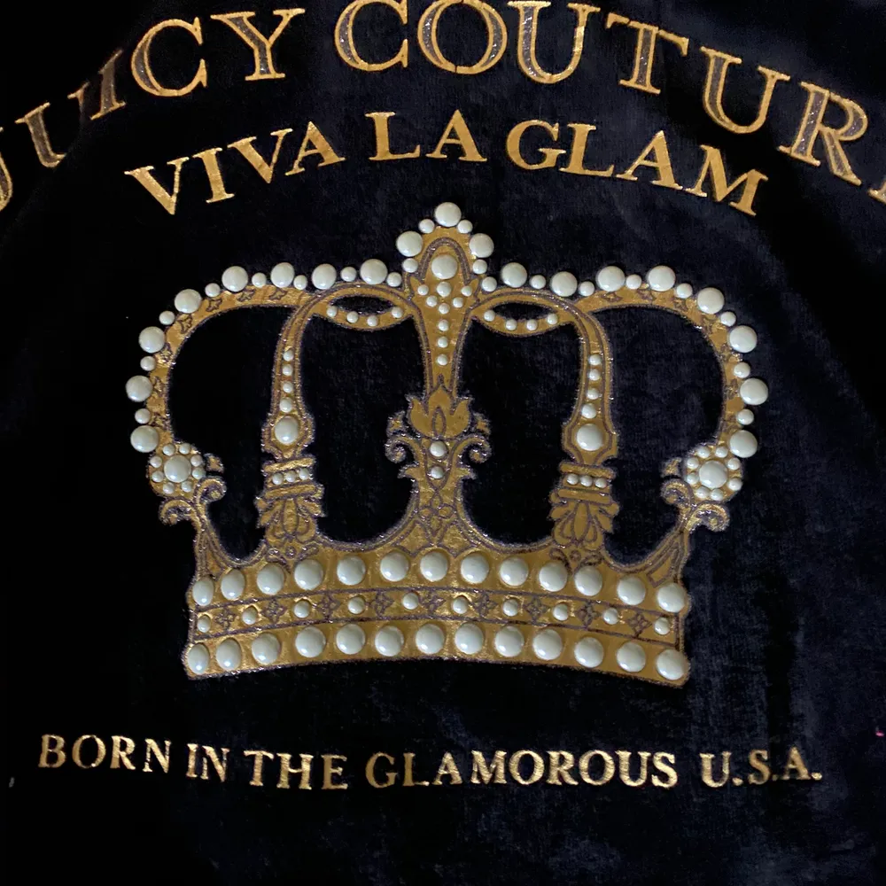 Svart Juicy Couture hoodie i mjukaste velour. ”Logo velour viva crown, Robertson jacket, pitch black”. Använd fåtal gånger, superfint skick. Stl M i tröjan men liten i storlek, motsvarar en stl S. Längd från axel ca 58cm. Två fickor fram. Gulddetaljer med vita stenar/pärlor i kronan, glitter/bling i Juicyloggan. Köpt på Juicy’s hemsida, nypris 1999kr + tull från US. Säljes för 500kr + spårbar frakt 63kr.. Hoodies.