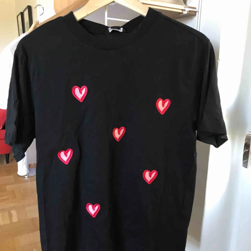 Helt oanvänd svart T-shirt från monki med broderade hjärtan. Prislapp kvar, storlek XS passar som S. T-shirts.