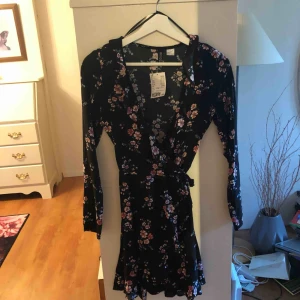  - Blommig omlottklänning från HM i storlek 34, aldrig använd och lappen är kvar. Superfin inför sommaren! Säljes då den är för liten för mig. Nypris 199kr. Kan mötas upp i Karlstad eller fraktas inrikes (frakt ingår ej, fraktas i vadderade kuvert)