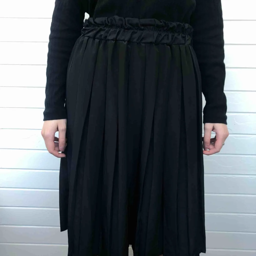 Veckad kjol från Gulins i glansigt tyg. Den är i 42/44 men den tidigare ägaren har 38. Den är i bra begagnat skick och har inga fläckar eller hål. Den är gjord i Storbritannien. Den är gjord i 100% polyester.   Personen på bilden är 158 cm lång.. Kjolar.