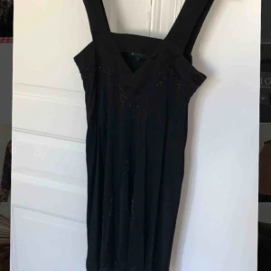 - Jättefin svart knälång sidenklänning från Tiger of Sweden med dekorativa påsydda pärlor. Storlek medium. Använd en gång.
