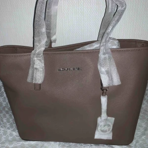  - Äkta, oanvänd Michael Kors-väska -Jet set handväska  med logtyp och detaljer i silverfärg. 