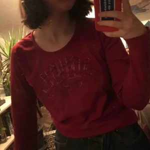  - Röd långärmad tröja med urringning och glittrigt tryck. Väldigt 90/00-tal i använt skick. Passar mig som är S