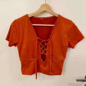  - Röd/brun croptop med snörning i mitten. Aldrig använd. Mjukt tyg.