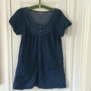  - Jeansklänning, två fickor fram, 4 klädda tygknappar fram. Fint skick. 100% bomull. 