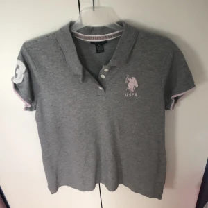 US polo assn. Polo-tröja - Strl: XL, grå med babyrosa. Använd 1-2 gånger. Bra skick. Nypris: 500kr Mitt pris: 150kr (går att förhandla). Köparen står för frakten! 🌸