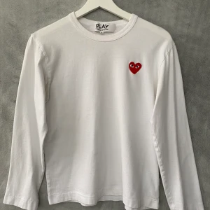 Vit Comme des Garçons långärmad - En långärmad vit tröja från Comme des Garcons play. Inte jättemycket använd, bra skick. Köpt på NK för cirka 1200kr. Storlek S, axelbredd: 45cm, ärmlängd: 53cm och totala längd 57cm. Pris kan förhandlas. Kontakta för mer info om leverans osv.