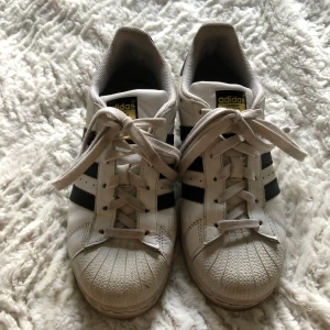 Adidas Originals Sneakers Superstar J - Märke : Adidas Orginals  Typ : Sneakers  Storlek : 36  Modell : Superstar  Material : Skinn  Färg : Vit  Kroppstyp : Kvinna  Skick: begagnade, har små slitningar på insida hälar.