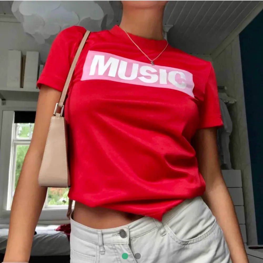 Helt oanvänd röd t-shirt från acne i glansig syntet. Rosa tryck med motivet ”music”. Så cool men misstänker att den skulle komma mer till nytta i någon annans garderob 🕺. T-shirts.