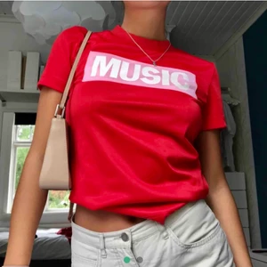 Acne t-shirt - Helt oanvänd röd t-shirt från acne i glansig syntet. Rosa tryck med motivet ”music”. Så cool men misstänker att den skulle komma mer till nytta i någon annans garderob 🕺