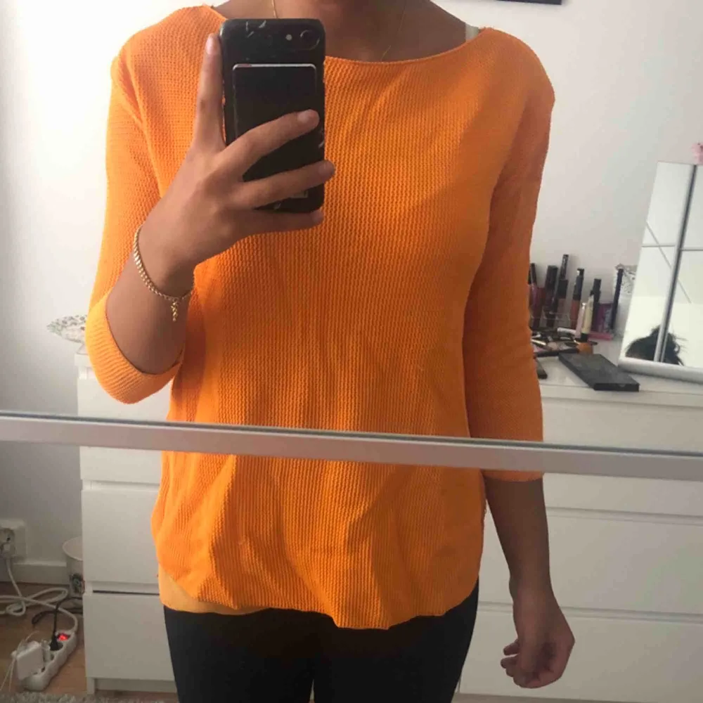 En tunn stickad tröja i en mycket fin orange färg som verkligen sticker ut då den är unik! Det är i storlek M men passar även personer som brukar ha XS eller S. Jag är 162 cm och den sitter så som det ser ut på bilderna.. Stickat.
