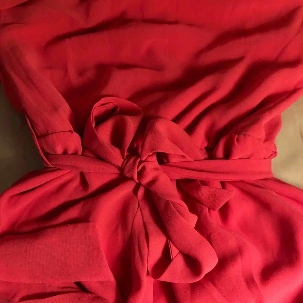 Rosa klänning som går ungefär till knäna Ena axeln är bar och klänningen knyts med snöre i midjan. Klänningar.