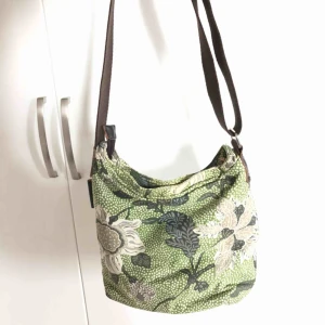  - Superfin tygväska från märket Ceannis i grönmönstrat tyg. Brett axelband som kan justeras i längd. Finns tre innerfack och kan stängas med både dragkedja och knapp. Säljs för att den förtjänar att användas mer än jag gör :)