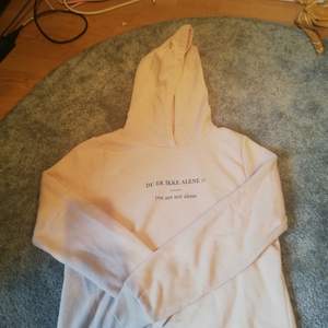 En ljusrosa hoodie från gina med trycket DU ER IKKE ALENE vilket är ett citat från den norska serien SKAM. En liten ljus fläck finns på vänster arm men annars är den ok. 