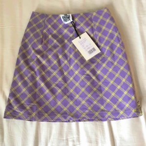 Rutig kjol från The Ragged Priest - Ljuslila kjol med gula detaljer (dragkedjor i sidorna) från The Ragged Priest. Säljer då den tyvärr inte passade och tiden för att returnera gått ut🥺 Köpt för 450kr på Zalando! Frakt ingår i priset💜💛