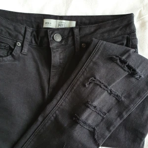 Highwaist jeans med hål - Aldrig använda svarta, tuffa jeans. Highwaist. Köpta i England på Topshop för ca 4 år sedan. Hål längst med båda benen på framsidan. Riktiga fickor fram och bak. Frakt inkluderat i priset! 