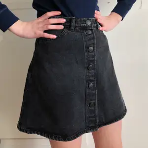 Kjol från Monki. I svart denim med knappar längs framsidan. Relativt högmidjad. Klockad i passformen. Strl: 36. CN: 165/68A. Längd: 42 cm. Vikt: 365 g. Samfraktar gärna! 