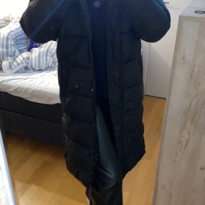 Lång dun jacka  - Använd 2 gånger. Lång dun jacka i ungefär knähöjd. Extremt varm och skön med två sidofickor, luva och knäppen vid sidorna som går öppna. Köparen står för frakt. 