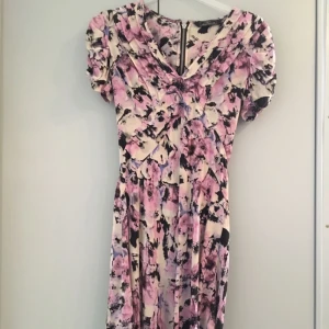  - Kort mönstrad klänning i siden. Synlig dragkedja bak. Rynkat tyg över axlar. Fint skick inga fläckar.