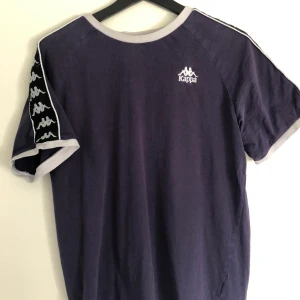 Kappa T-shirt strl. M - Köpt hösten 2018 från Zalando, i storlek M. Nypriset var 300, säljer då jag har vuxit ur den. Färgen är lila/blå. Jag har använt den ganska mycket men den är ändå i gott skick. Frakt 80 riksdaler. Hör av er!
