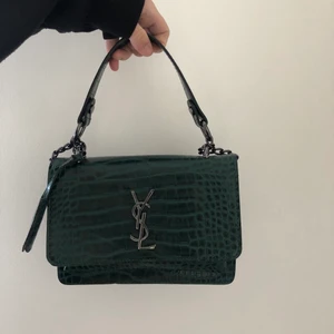 YSL crossbody bag - Jättefin krokodilmönstrad YSL look-a-like i mörkgrönt. Köpt på cypern förra året, använd några gånger men den har inte helt fått den kärleken den förtjänar, därför söker den nu ett nytt hem!