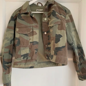 Croppad camouflage jeansjacka  - En kort jeansjacka i färgen camouflage från Gina Tricot i storlek M men skulle säga att den passar en S också. Använd bara några gånger så den är i väldigt bra skick. Säljes pga att jag inte använder den