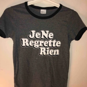  - Grå T-shirt med svarta detaljer i ärmar och halsmudd. Vit text. Sitter bra och stretchig