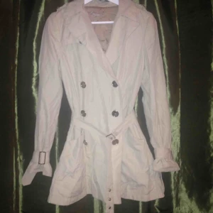  - Supersnygg Beige kort trench coat med silvriga knappar och spännen i lätt använt skick, från tidigt 2000 tal!  Frakt ingår ej :/