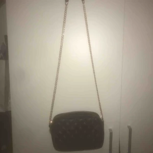  - En svart crossover väska från hm som går ungefär ner till höfterna. Guldig kedja och ”vaddar” på sidorna. Stort utrymme inuti väskan.
