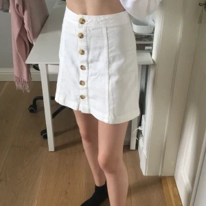 Vit kjol - Sommrig vit kjol. Sitter skönt överallt. Fina bruna knappar. Den är helt oanvänd (prislappen är kvar). Köparen står för frakt eller möts upp i Sthlm. Betalas via swish✨