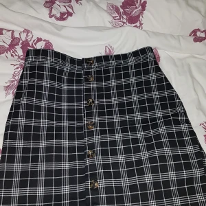 Svart- och vitrutig kjol i strl 40 - Kortare svart- och vitrutig kjol i storlek 40, bra passform och inte för stor. Har använts endast ett fåtal gånger och är därmed i fint skick.