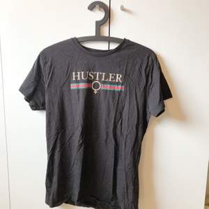 svart t-shirt med texten ”hustler” i gucci stil på bröstet. köpt på madlady för några år sedan och finns ej att beställa på deras sida längre. väldigt bra skick, knappt använd. storlek L men är liten i storleken så sitter mer som en M