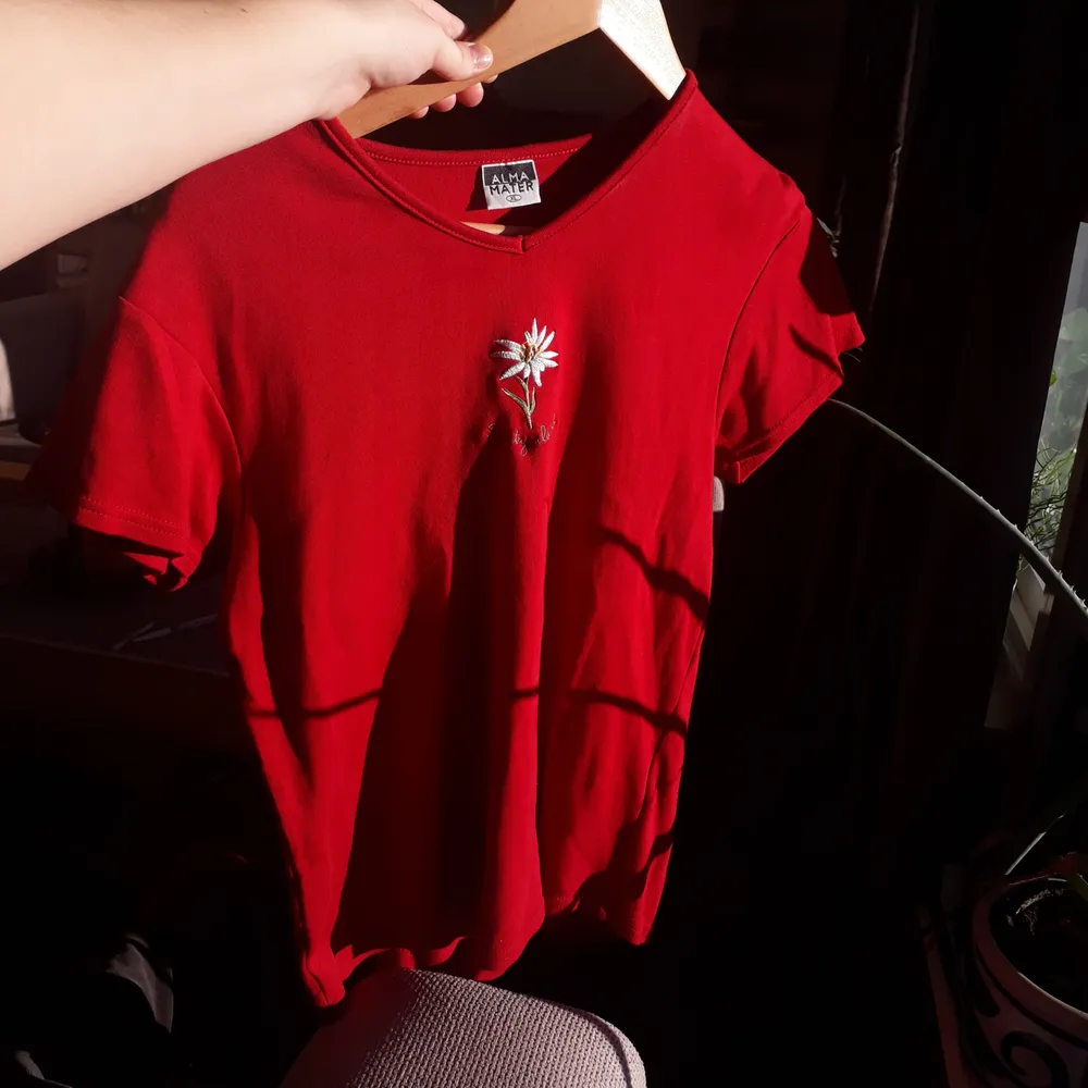 En röd t-shirt med en gullig broderad blomma på. Det står XL men passar mer som en M/L. T-shirts.