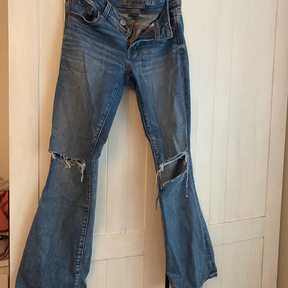 American eagle blåa bootcut/flare jeans med hål, har klippt till lite i det vänstra hålet själv så det är lite större än det på högerben. Strl 4 skulle säga att det motsvarar en s/36/38. Jeans & Byxor.