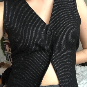 Väst med glitter  - En väst jag köpt på second hand. 46 i herrstorlek, skulle säga att den passar en M. Säljer pga för stor för mig. Den är svart på baksidan och har ett spänne som man kan dra åt. 